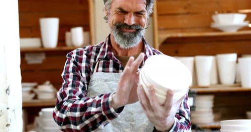 Potter Inspects Finished Ceramics in His Workshop