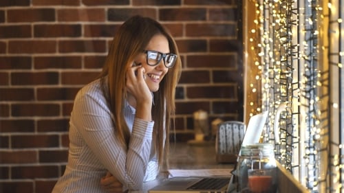 Cheerful Young Businesswoman Talking on the Phone in a Cafe