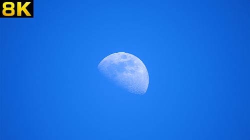 Moon Glides Across a Clear Blue Sky