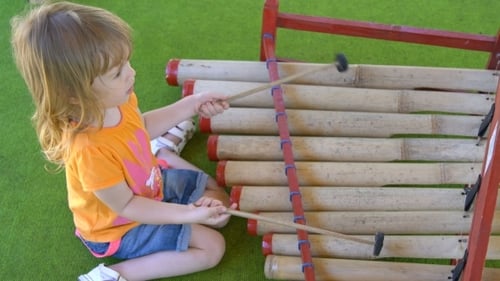 Young Child Plays a Wooden Xylophone
