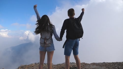 Man and Woman Standing on the Edge of Beautiful Canyon, Victoriously Outstretching Arms up