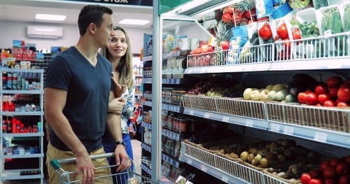 Guy and a Girl Near the Counter of Vegetables and Fruits in the Store / A Couple in a Supermarket