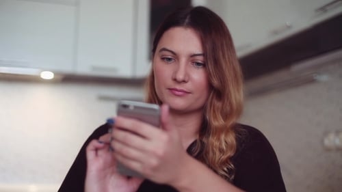 Beautiful Young Girl Uses the Internet with a Smartphone. Home Style.