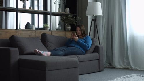 Woman Lounges on Sofa, Child Approaches