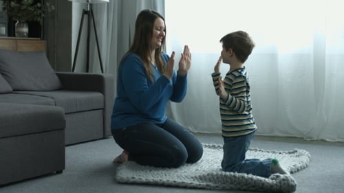 Mother and Boy Playing Hand Game at Home