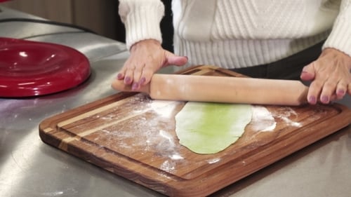 Cropped Shot of a Woman Rolling out Green Dough with Herbs for Pasta