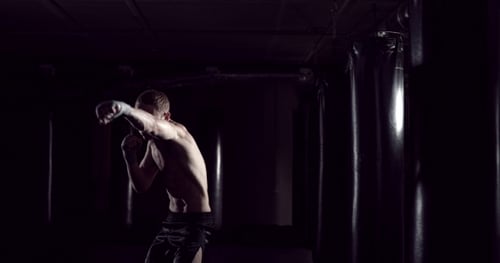 Athletic Man Boxing in Dark Gym