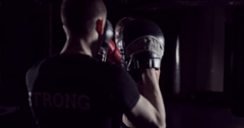 Boxer Man Hits Punching Bag with His Fists Trainer Holds. Boxer Hits Punching Bag That Her Partner