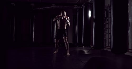 Man Practices Martial Arts in Dark Gym