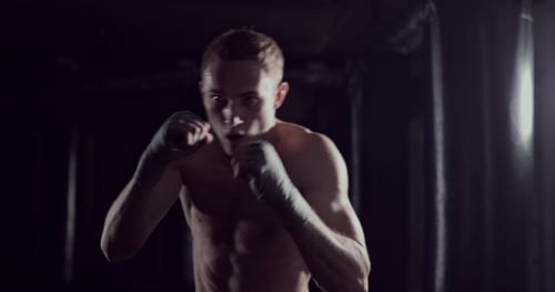 Kickboxer Shadow Boxing als Übung für den Kampf. Schlagtraining beim Kämpfertraining. Boxen im Dunkeln