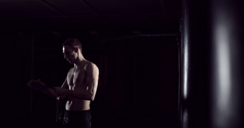 Muscular Man Wrapping Hands for Boxing Workout