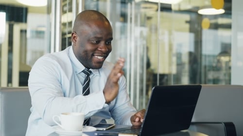 Man Smiling and Waving During a Video Call