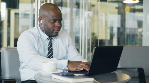 Man Works at Laptop with Coffee at Workplace