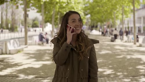 Smiling Young Woman Talking on Phone in Park.