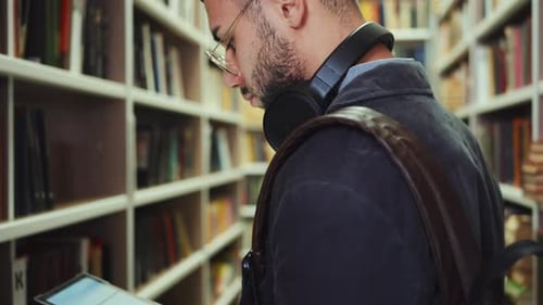 Student using tablet to find book in library