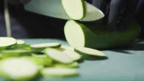Cook's Hands in Black Gloves Slicing Zucchini Close Up Selective Focus