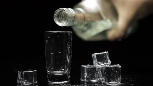 Glass Bottle Filling a Small Drink Glass