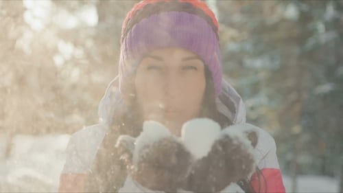 Woman Blowing Snow in a Snowy Forest