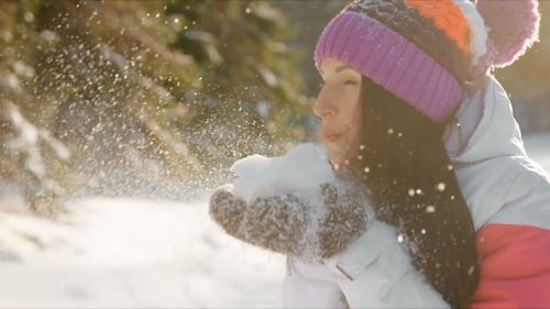 Woman Blowing Snow in Sunny Winter Landscape
