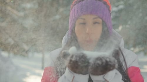 Cheerful Woman Blowing Snow in Winter Forest