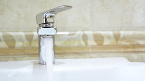 Shiny Faucet Dispensing Water in Modern Bathroom