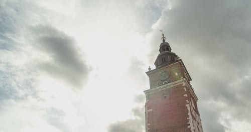 Alter Rathausturm mit Uhr. Wolken im Hintergrund.