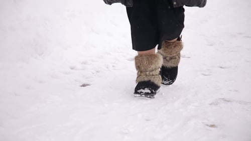 Woman Walks in Fur Winter Boots Through Snow