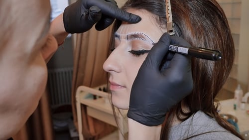 Makeup Artist Drawing Lines on Woman's Face