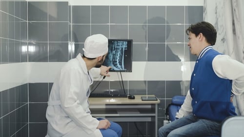 Ein Arzt, der einen Patienten untersucht, zeigt die verletzte Wirbelsäule auf dem Monitor