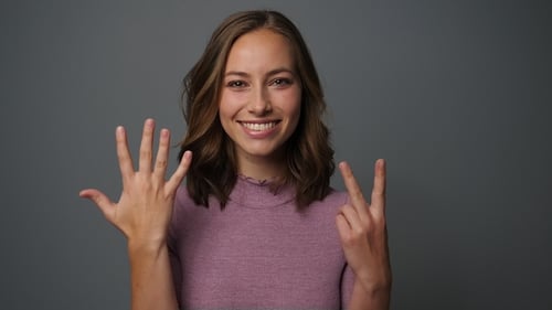 Smiling Woman Shows Seven with Hand Gestures
