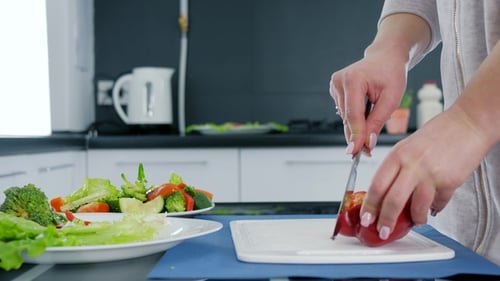 Hände einer Frau mit Messer zum Schneiden von süßem rotem Pfeffer für Salat auf Schneidebrett, Gesundes Essen