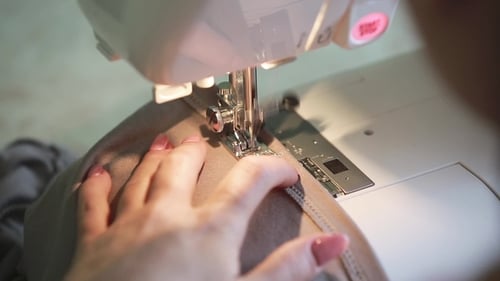 Hands Using Sewing Machine to sew Cloth