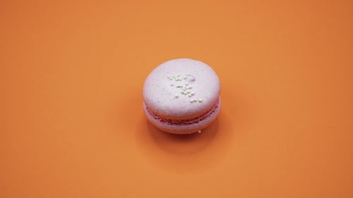 Pink Macaroon with Sprinkles on Orange Surface