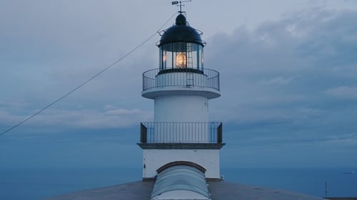 Illuminated Lighthouse Guiding Ships at Dusk