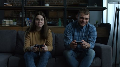 Couple Playing Video Games on Sofa at Home