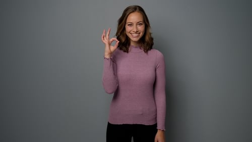 Smiling Young Woman Gives Okay Hand Gesture