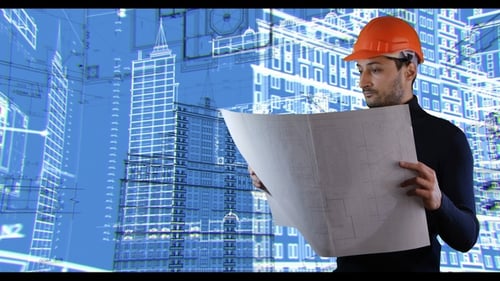 Ein Mann mit Schutzhelm liest Baupläne im Hintergrund der sich drehenden Baupläne