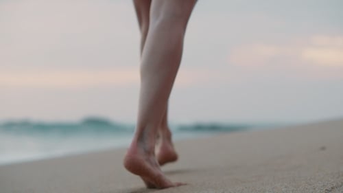 Female Feet Walking Along the Ocean Shore