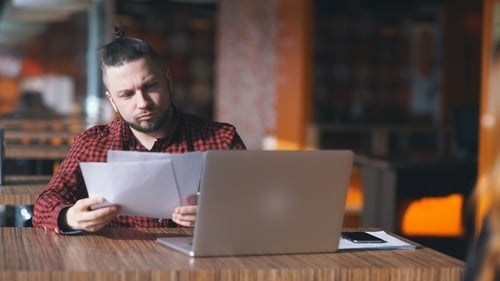 ein junger Freelancer untersucht Dokumente in einem Café