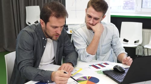 Männliche Geschäftskollegen erledigen gemeinsam Papierkram im Büro