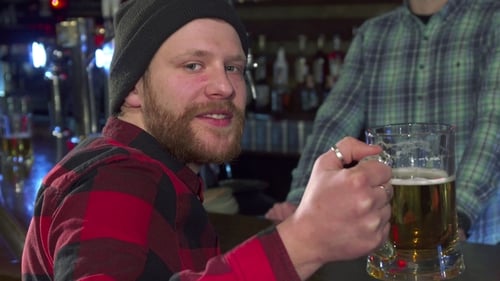 Bearded Man Drinking Beer at a Bar at Night