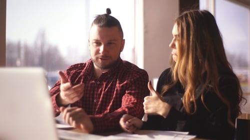 Coworkers Discussing Project on Laptop in Bright Workplace