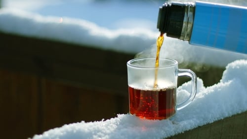 Tea Pour Down To Glass Standing on Snow at Tree Branch