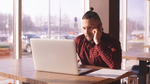 Young Adult Working on Laptop and Talking on Phone