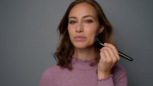 Smiling Woman Applying Makeup with Brush