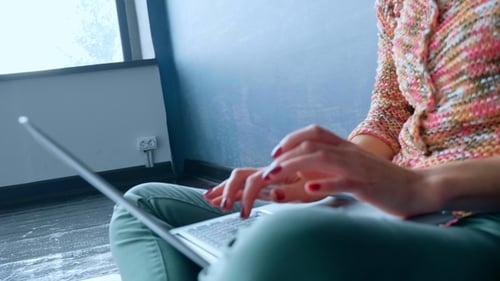Frau arbeitet drinnen am Laptop