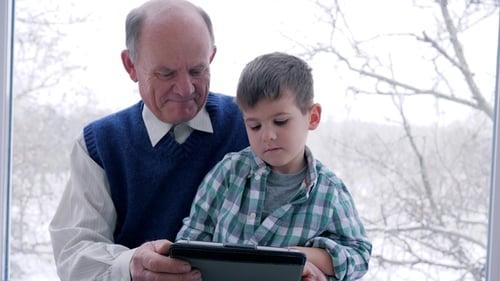 Grandfather and Grandson Using Tablet Indoors