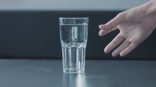 Mano de mujer recogiendo un vaso de agua