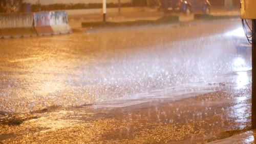 Tropischer Regen bei Nacht auf der Straße in Asien. Autos stehen und fahren bei starkem Regen