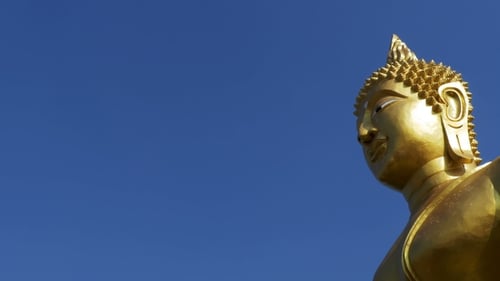 Statue of a Large Golden Buddha Against a Blue Sky in Thailand Temple